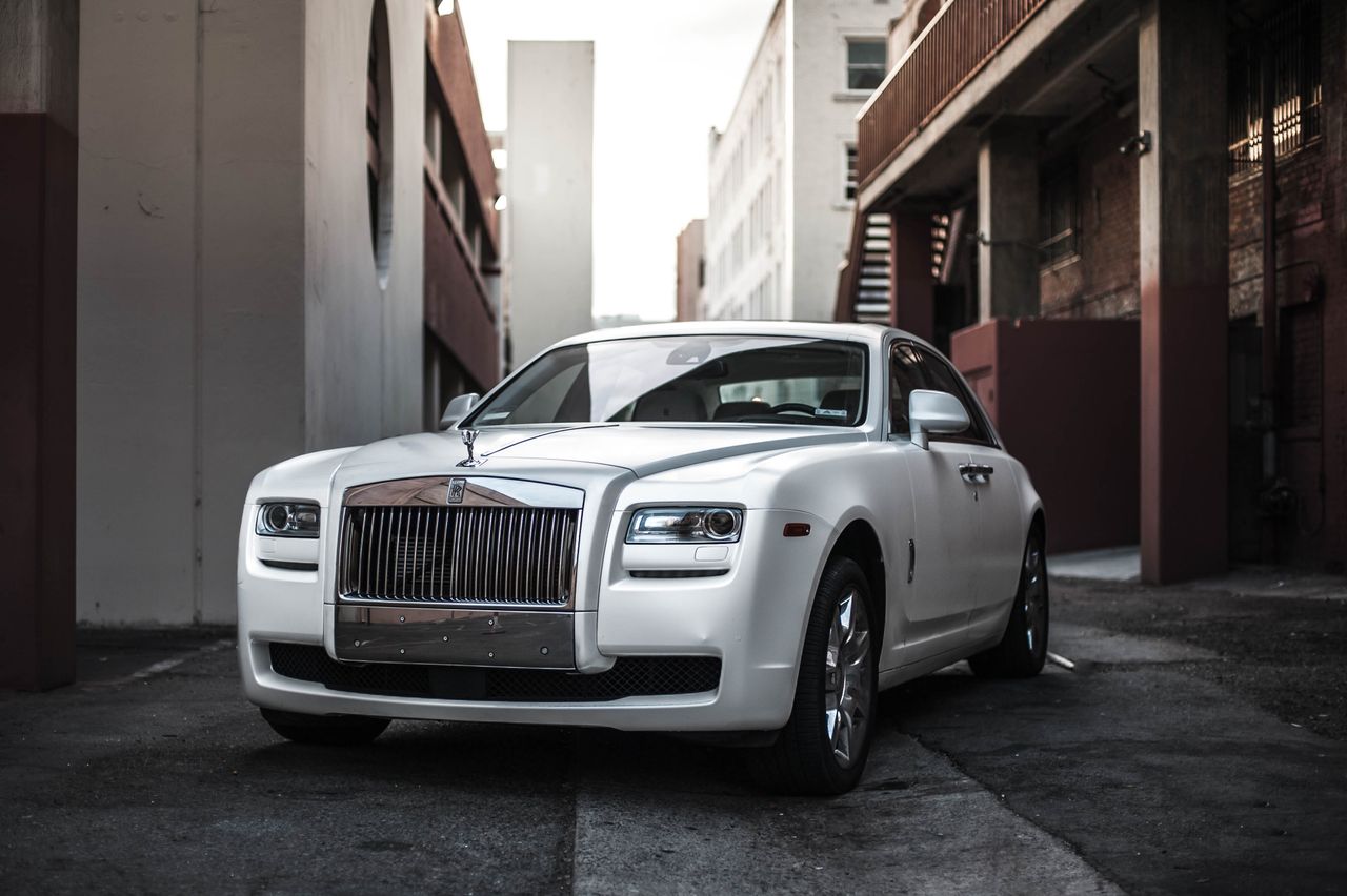 services-02 Elegant white luxury car parked in an urban alley, exuding sophistication and style.